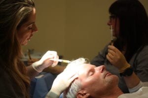 Two doctors administering hair loss treatment