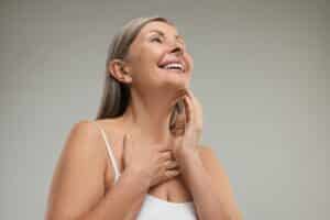 Woman touching her neck after a neck lift procedure.